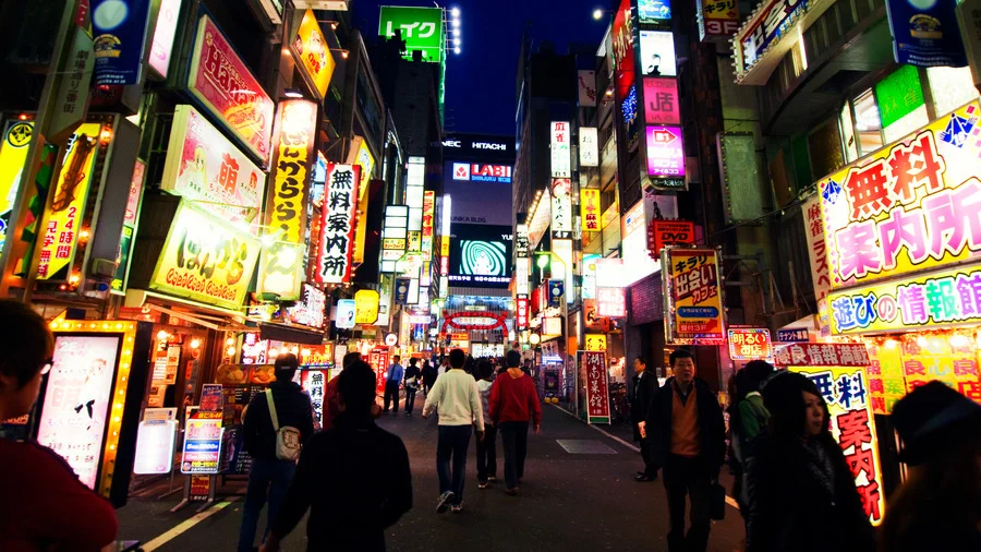 People walking and enjoying vibrant nightlife with neon lights in Shinjuku, Tokyo