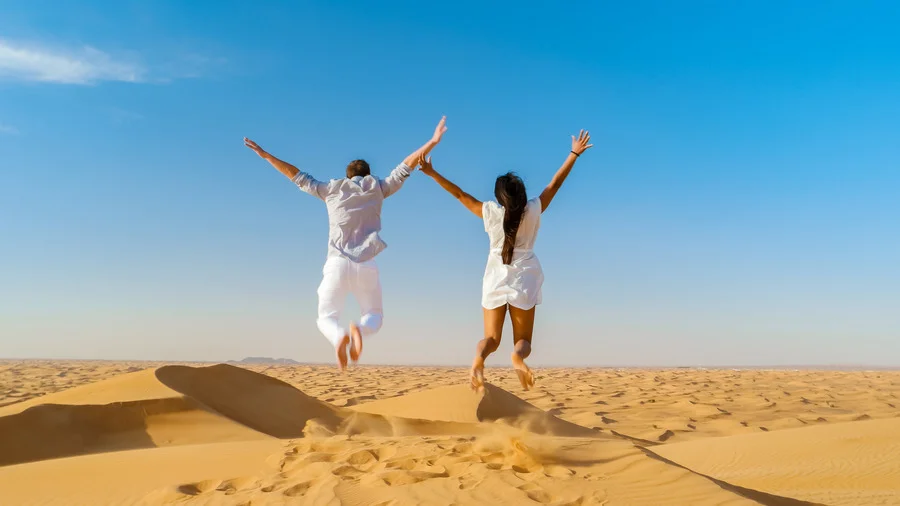 Couple enjoying a safari trip in the sand dunes of Dubai, United Arab Emirates.