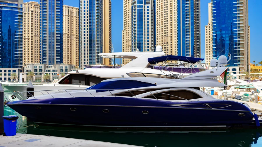 Luxury yacht in front of Dubai Marina skyscrapers, UAE