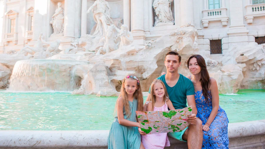 Family with Rome travel guide map enjoying near Fontana di Trevi, Rome, Italy.