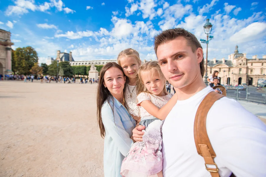 Family with two kids taking a selfie in Paris outdoors.