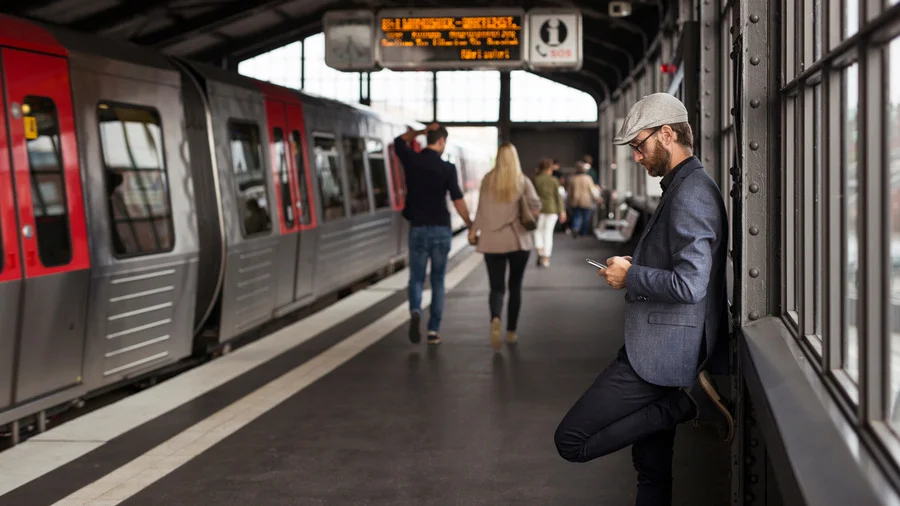 Man checking travel guide on phone at Paris Metro station with train in background