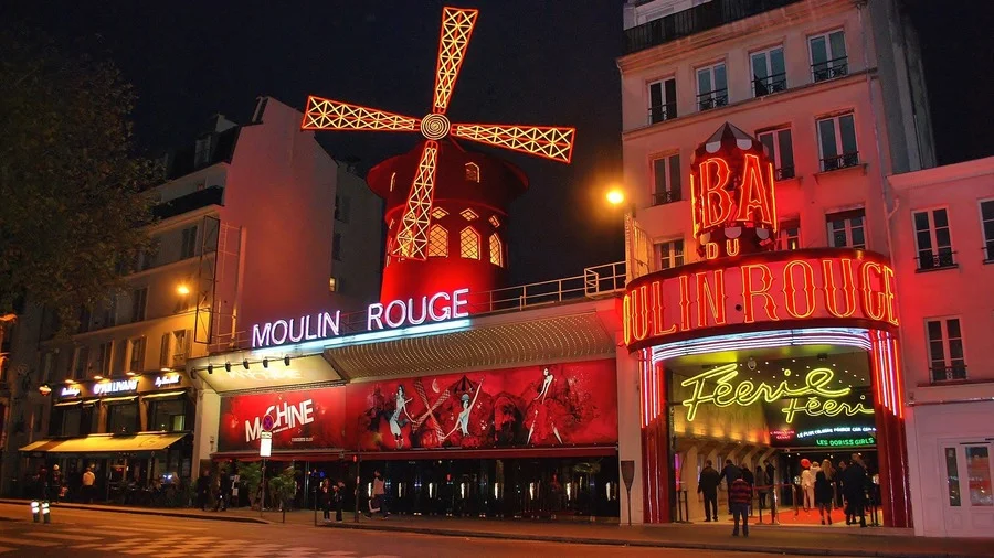 Moulin Rouge Paris at night under vibrant red lights, symbolizing Paris nightlife.