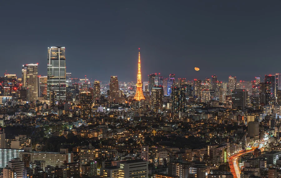 Tokyo Tower at night with city lights and moon in the background, Tokyo Travel Guide