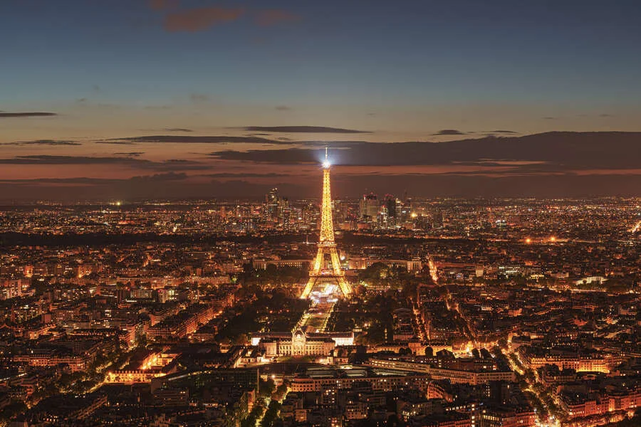 Aerial view of Eiffel Tower at night, illuminated amidst Paris city lights
