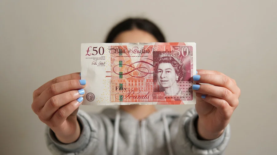 Woman holding a British £50 note in London