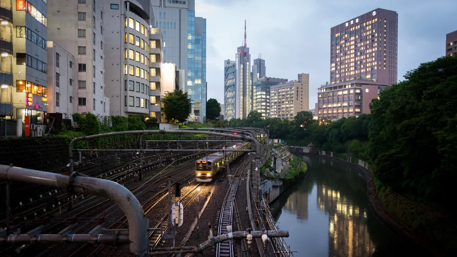 Winding train track and river cutting through the bustling streets of Tokyo, Japan