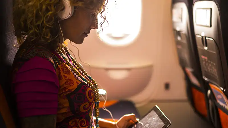 Caucasian businesswoman working on laptop inside an aircraft.