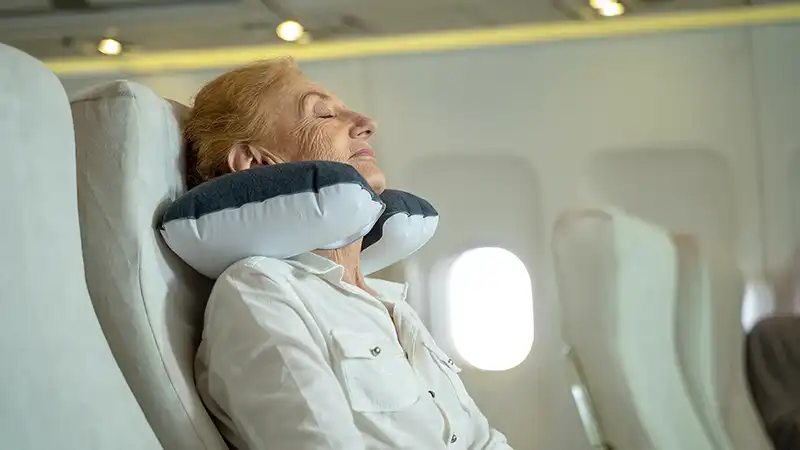 Elderly female passenger sleeping peacefully in her seat during a flight inside an airplane cabin