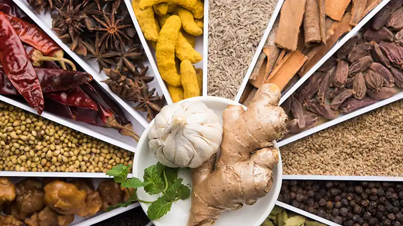 Variety of Asian spices on a platter, including turmeric, star anise, and cinnamon.