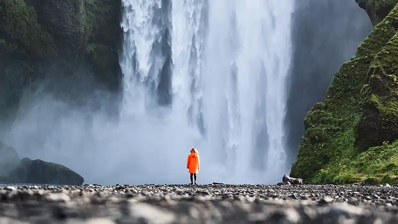 Tourist admiring the majestic Skogafoss Waterfall in Iceland.