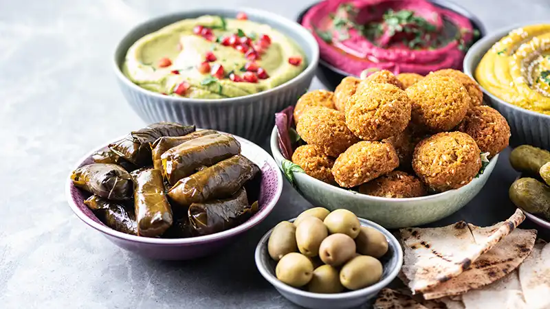 Middle Eastern Meze Assortment including hummus, pita, olives, pistachios, dolma, and falafel balls.