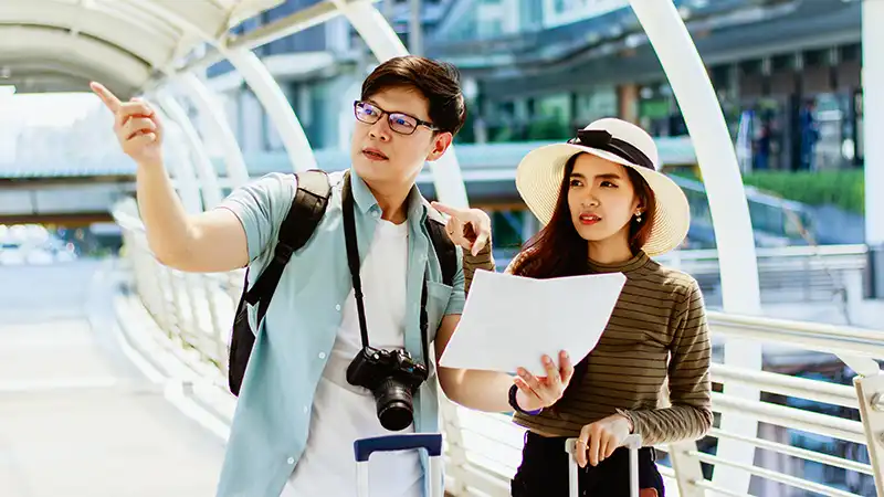 Young Asian male and female tourists consulting a Japan travel guide map