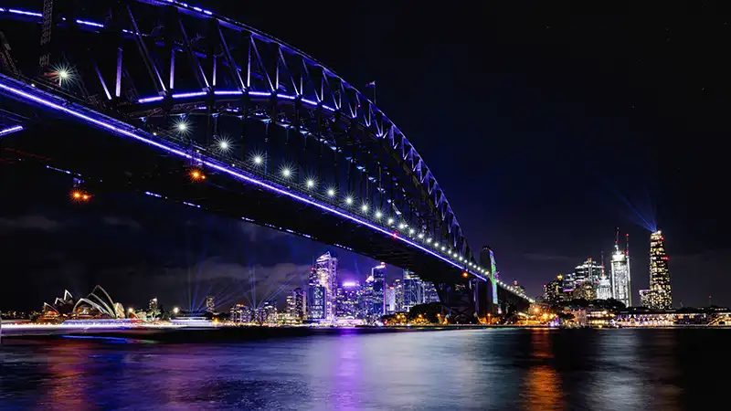 Sydney Harbour Bridge illuminated at night, a highlight in any Sydney travel guide.