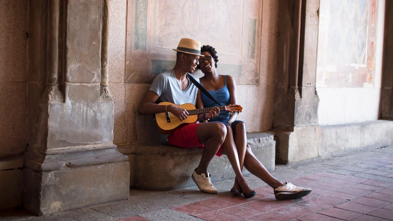 A young couple playing a mandolin in Havana, embodying the city's vibrant musical culture.