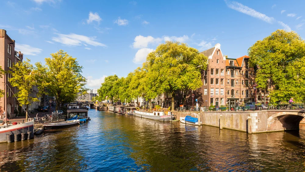 Scenic Amsterdam canal with vibrant city life, a top attraction for visitors.